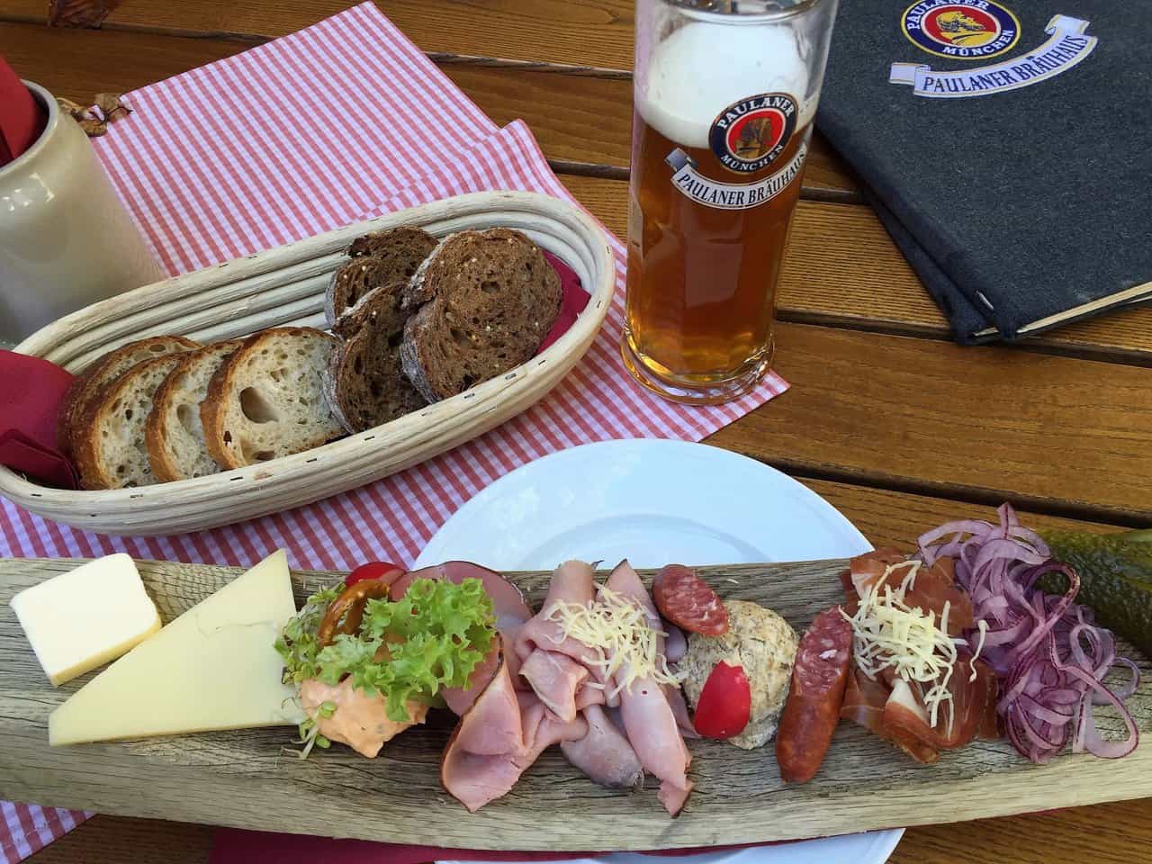 Traditional Bavarian cold cuts, cheese, bread, and beer served on a wooden platter at Paulaner Bräuhaus