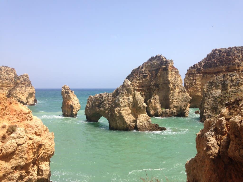 Dramatic limestone rock stacks and arches rising from turquoise water near Lagos, Portugal