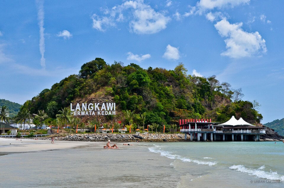 A mountain and a beach which a sign called "Langkawi" 