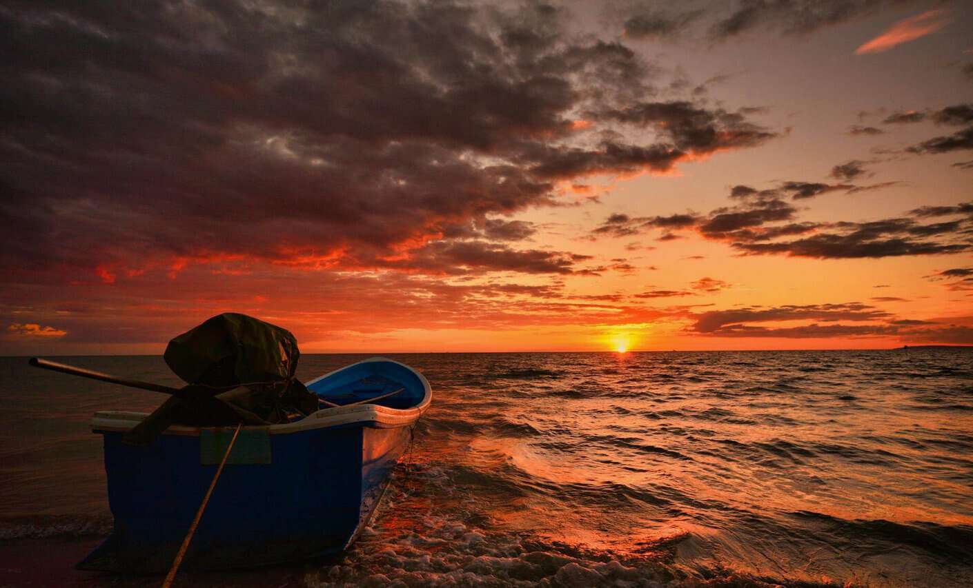 blue boat on sea during sunset