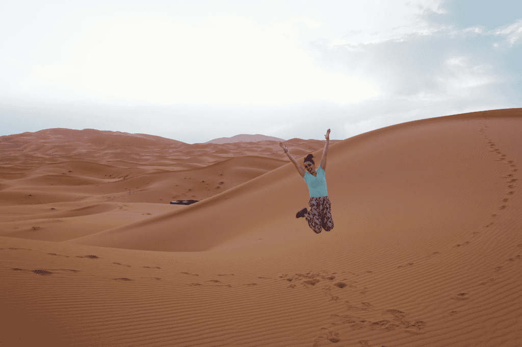 woman jumping in the sahara desert legs together