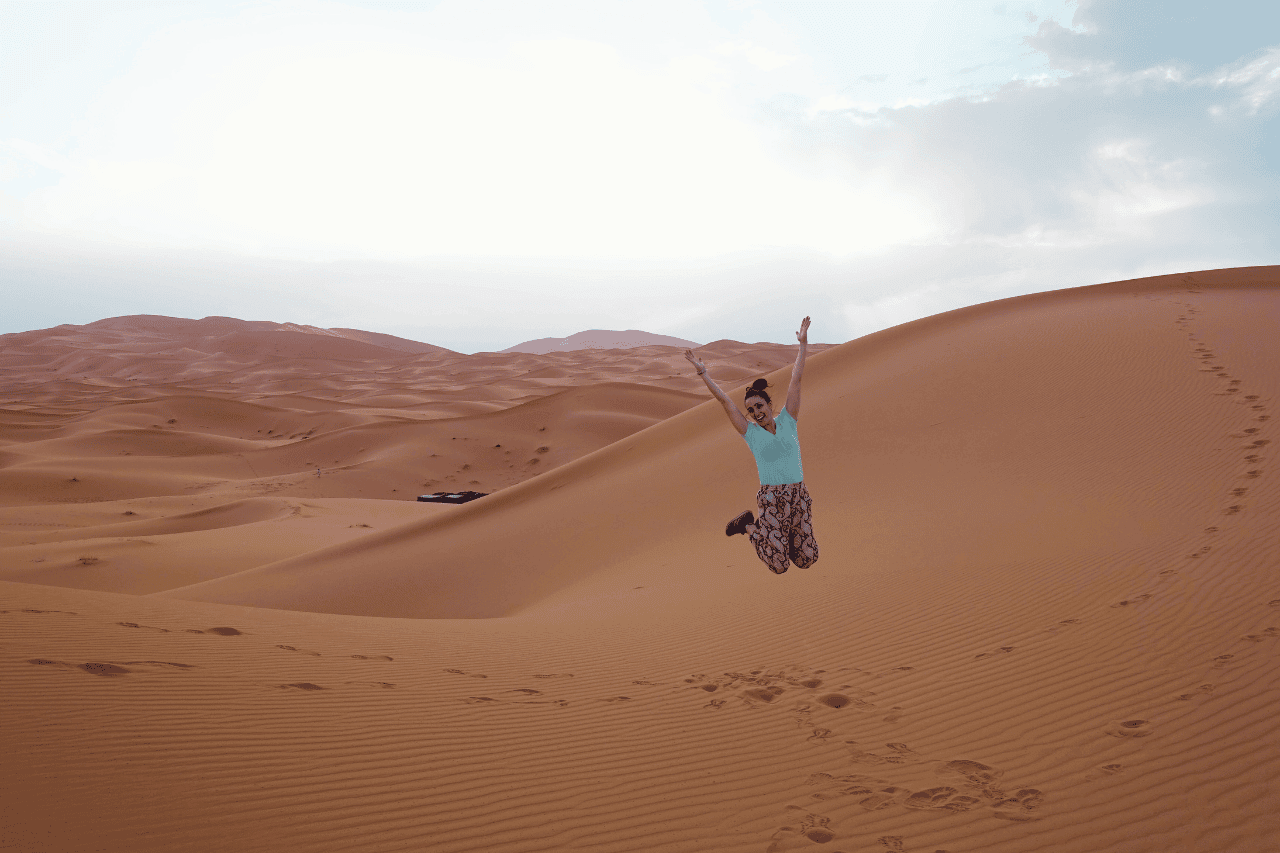 woman jumping in the sahara desert legs together