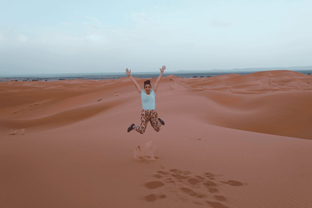 woman jumping in the sahara desert legs apart