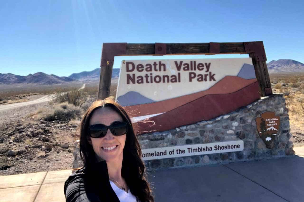 woman standing in front of the death valley sign