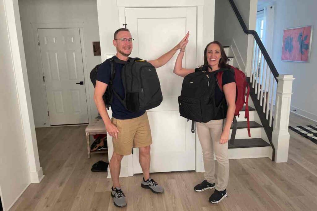 a man and a woman high fiving wearing backpacks excited about their travel packing checklist