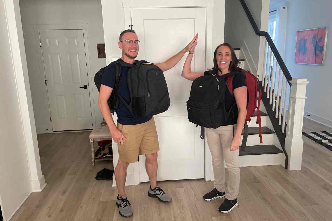 a man and a woman high fiving wearing backpacks, the woman is wearing a ladies backpack for travel