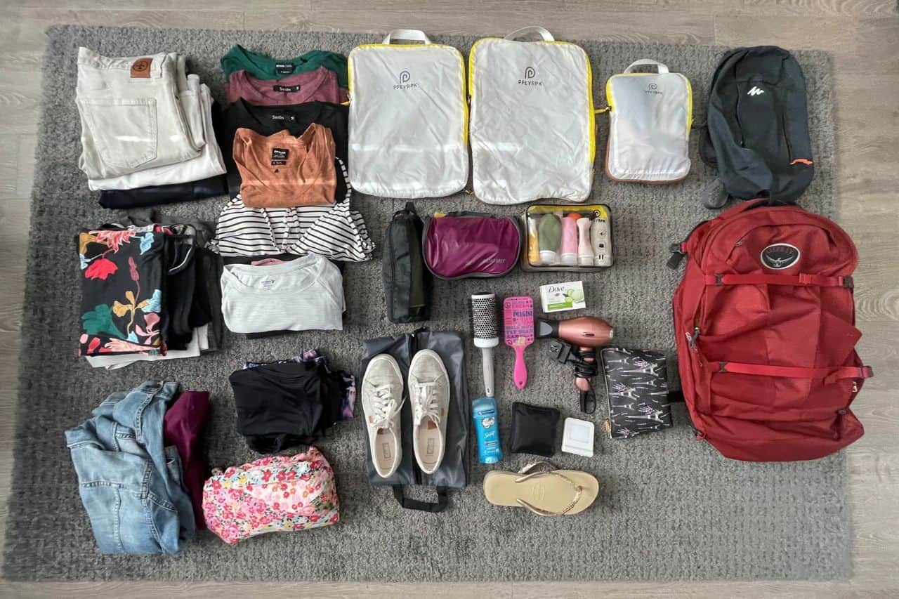 multiple travel items and clothes to show what fits inside of the osprey bag