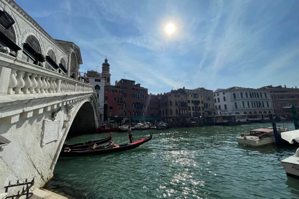 side view of the rialto bridge with a gondola passing underneath