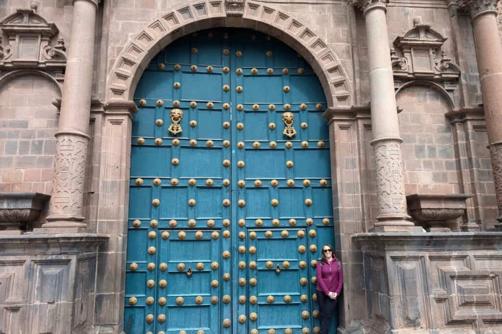 woman standing in front of a very large blue door in cusco