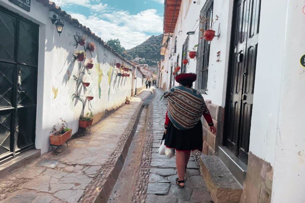 local woman wearing a red hat walking in cusco