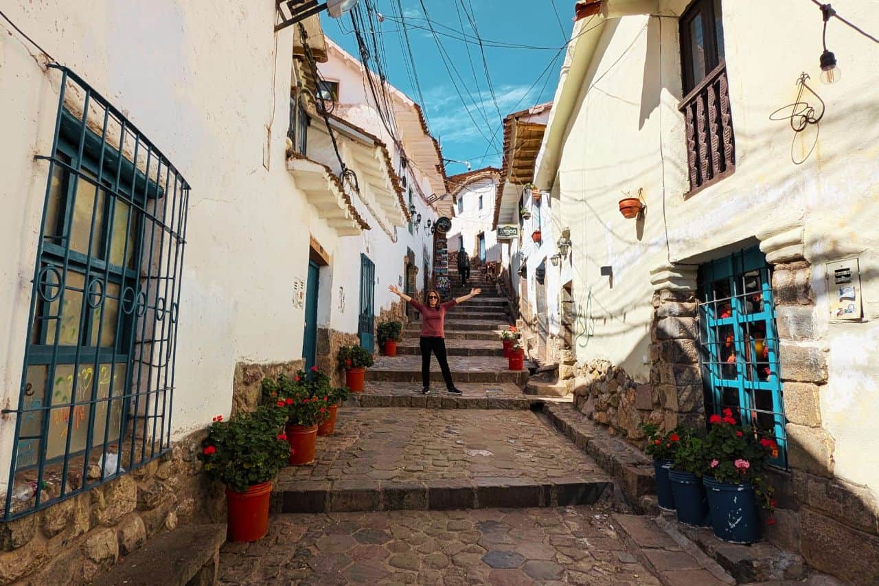 woman with arms wide on stone stairs in cusco