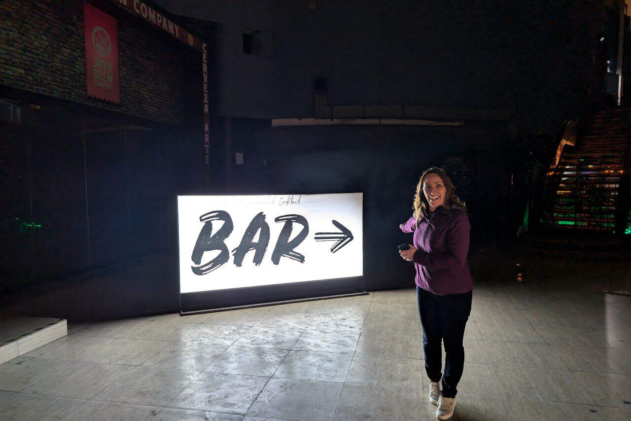 A woman posing in front of a bar sign – things to do in Lima.