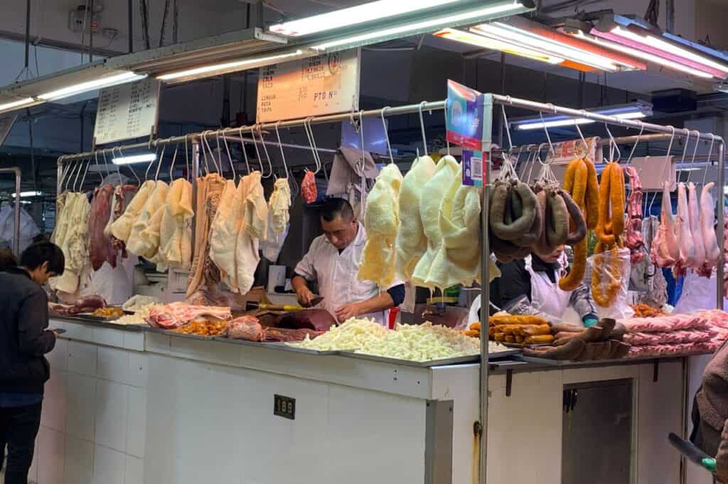 a man working at a food market at the butcher shop