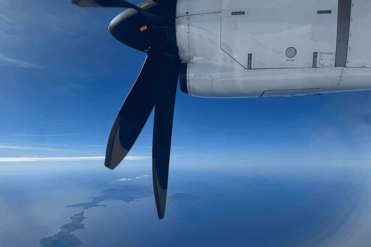 Blue Sky and a white prop plane flying through the air