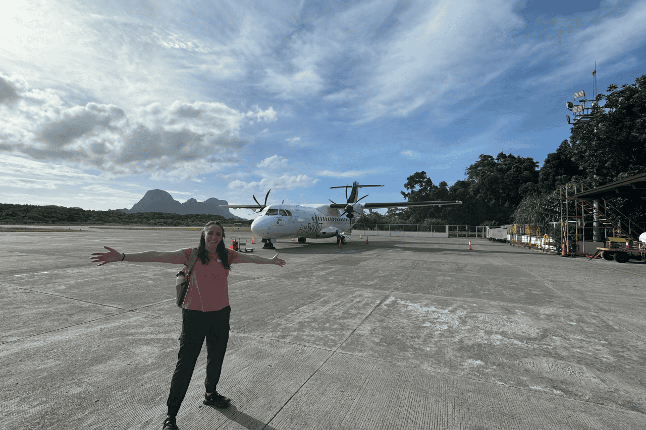 Woman standing on the runway at the airport in El Nido with her arms wide open