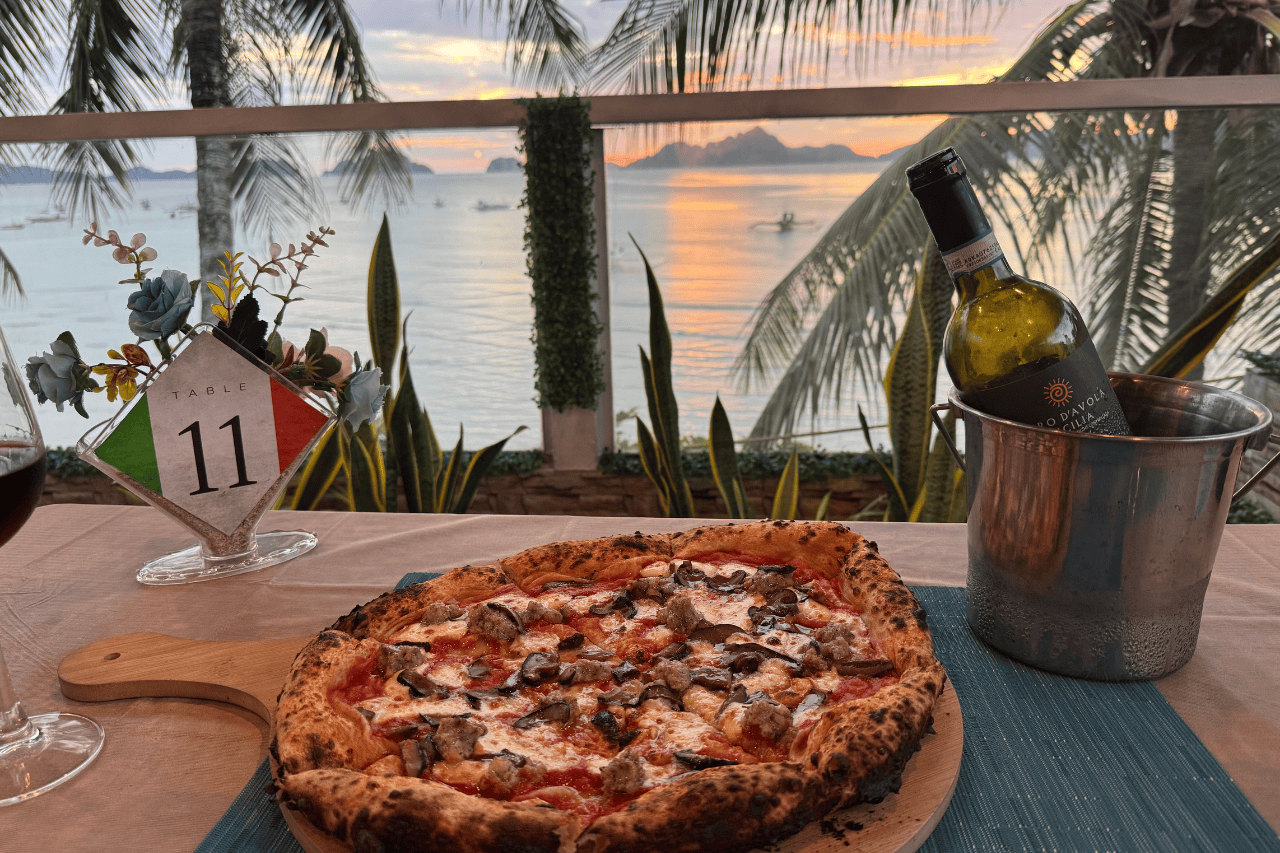 Large pizza pie with a sunset in the background at Mangio