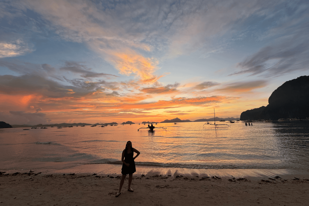 woman standing on the beaches in El Nido watching a sunset