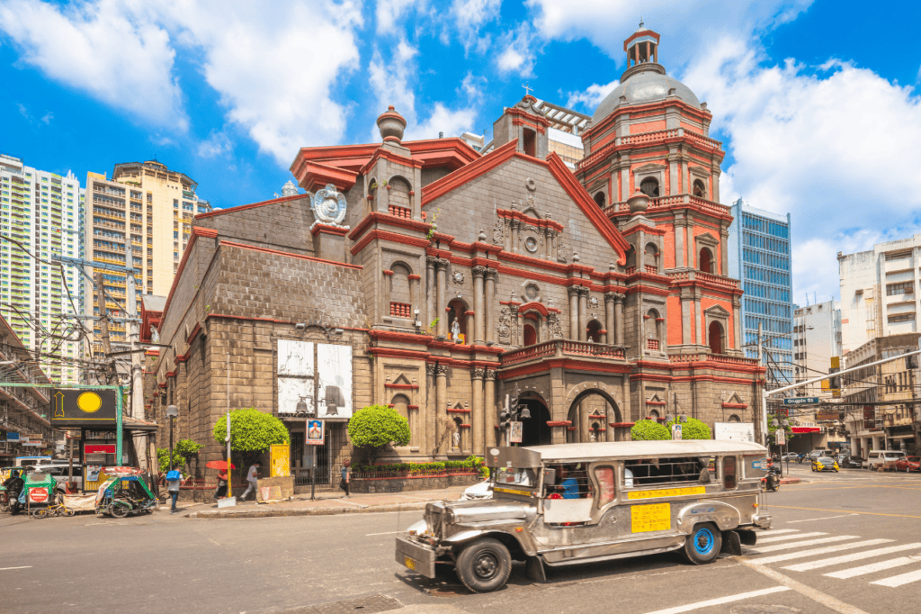 Silver Jeepney passing a church in Manila