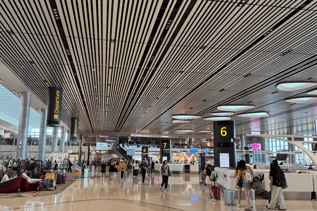 Busy airport terminal with travelers checking in – ensure you're covered with travel insurance for Singapore before your flight.