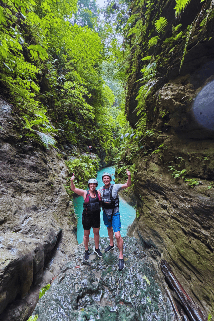 Tourists wearing life vests and helmets trekking through the canyon on a canyoneering tour.