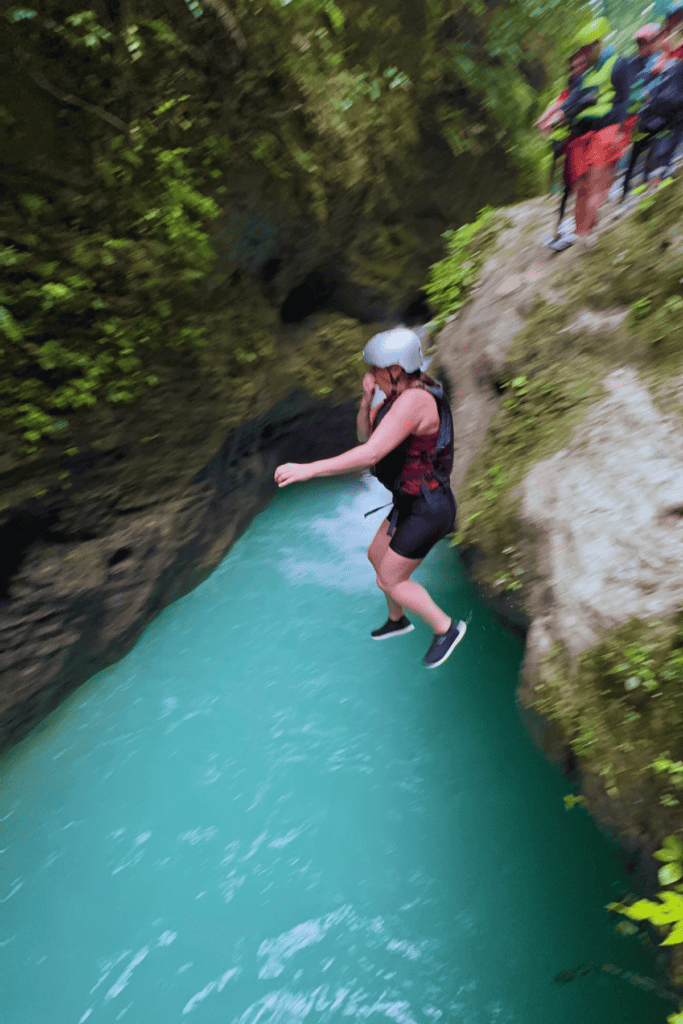 A woman jumping into the blue waters of the canyon near Moalboal