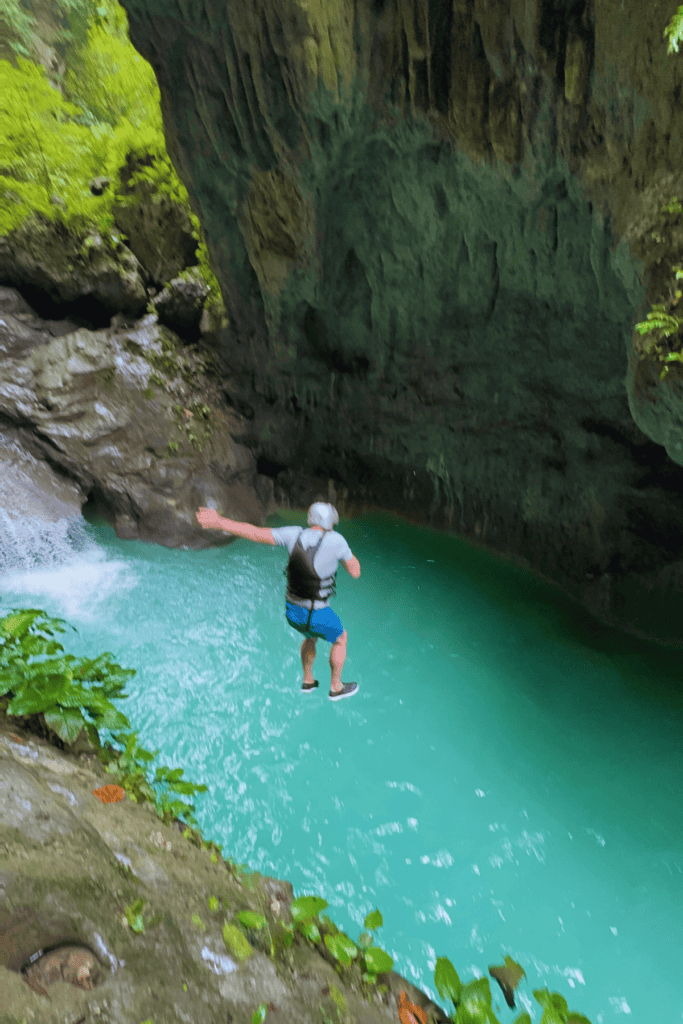 A brave canyoneer taking the highest jump of 12 meters into deep blue waters.