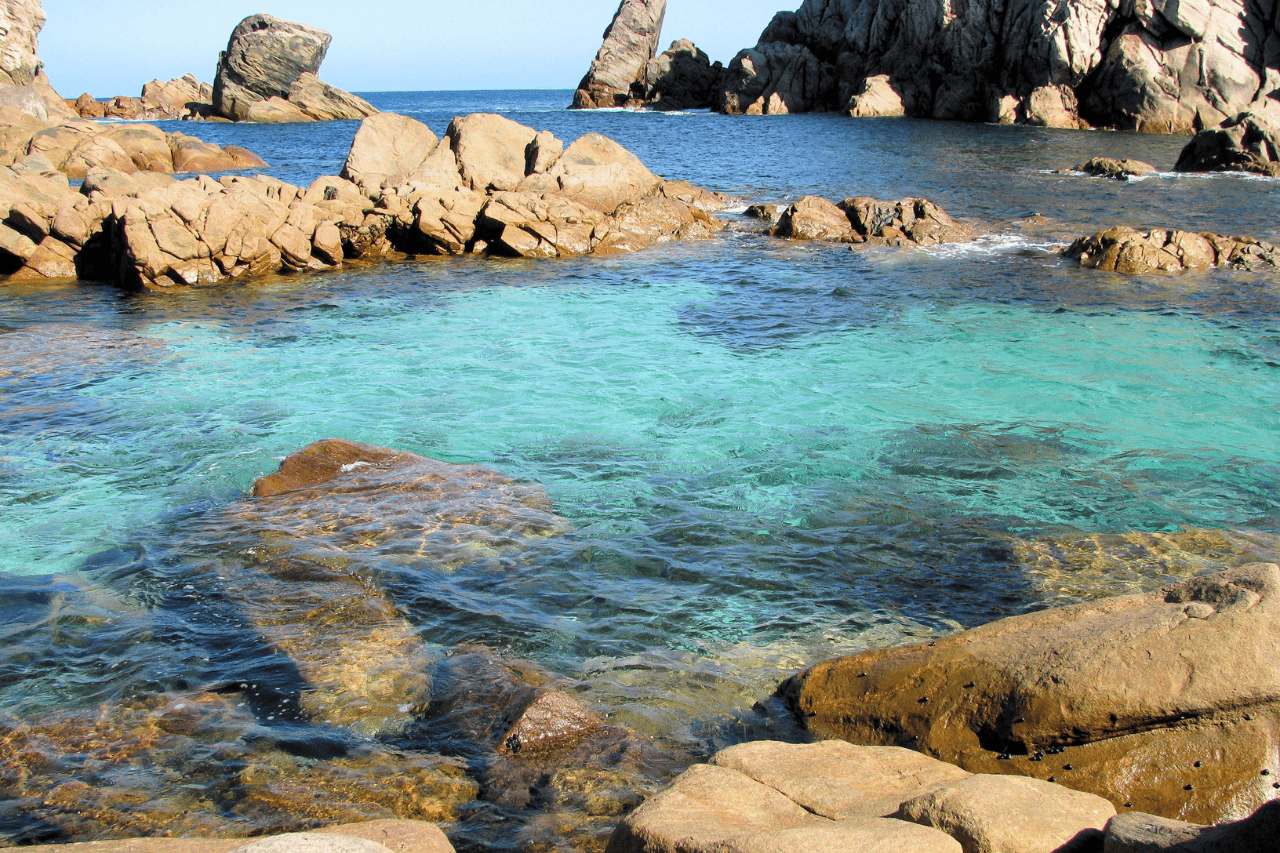 Magpupungko Rock Pools during low tide with swimmers in the clear water