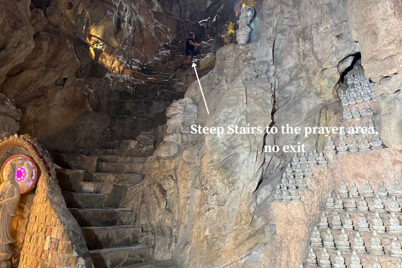 Narrow rocky stairs with sign pointing to secluded prayer zone inside Marble Mountains Vietnam cave