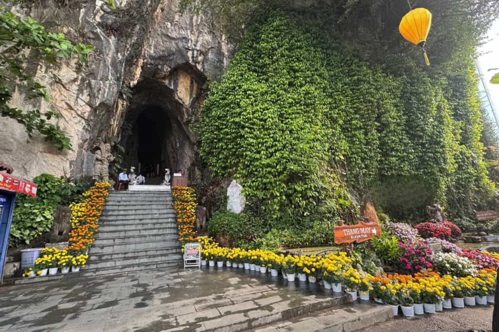 Stairs leading into Am Phu Cave with colorful flowers and a vine-covered cliff at Marble Mountains Vietnam