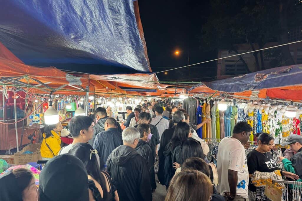 Tourists shopping for clothes and souvenirs in narrow aisle of Son Tra Night Market near Da Nang bridge
