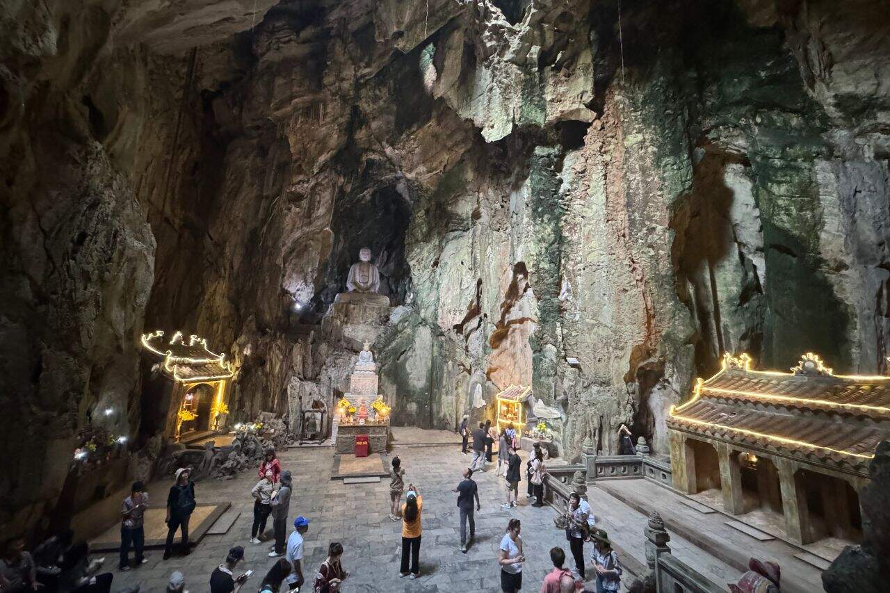 Tourists exploring Huyen Khong Cave with large Buddha statue inside Marble Mountains Vietnam