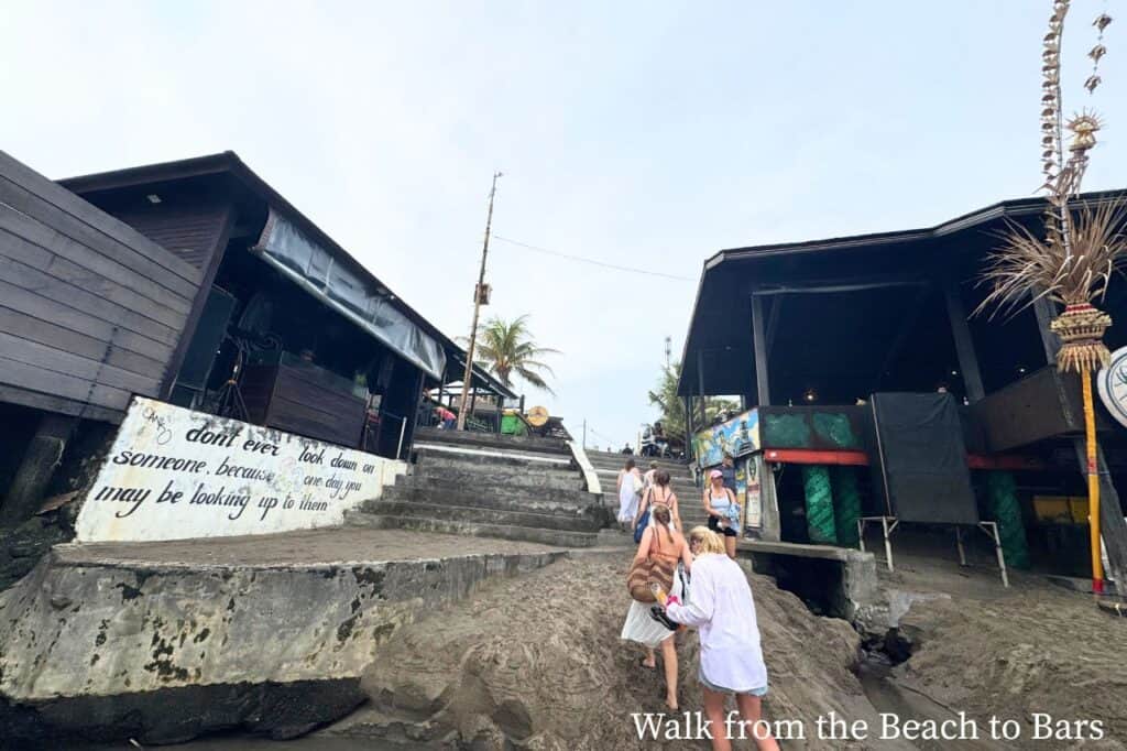 Pathway leading from beach in Canggu Bali to bars with people walking up the steps