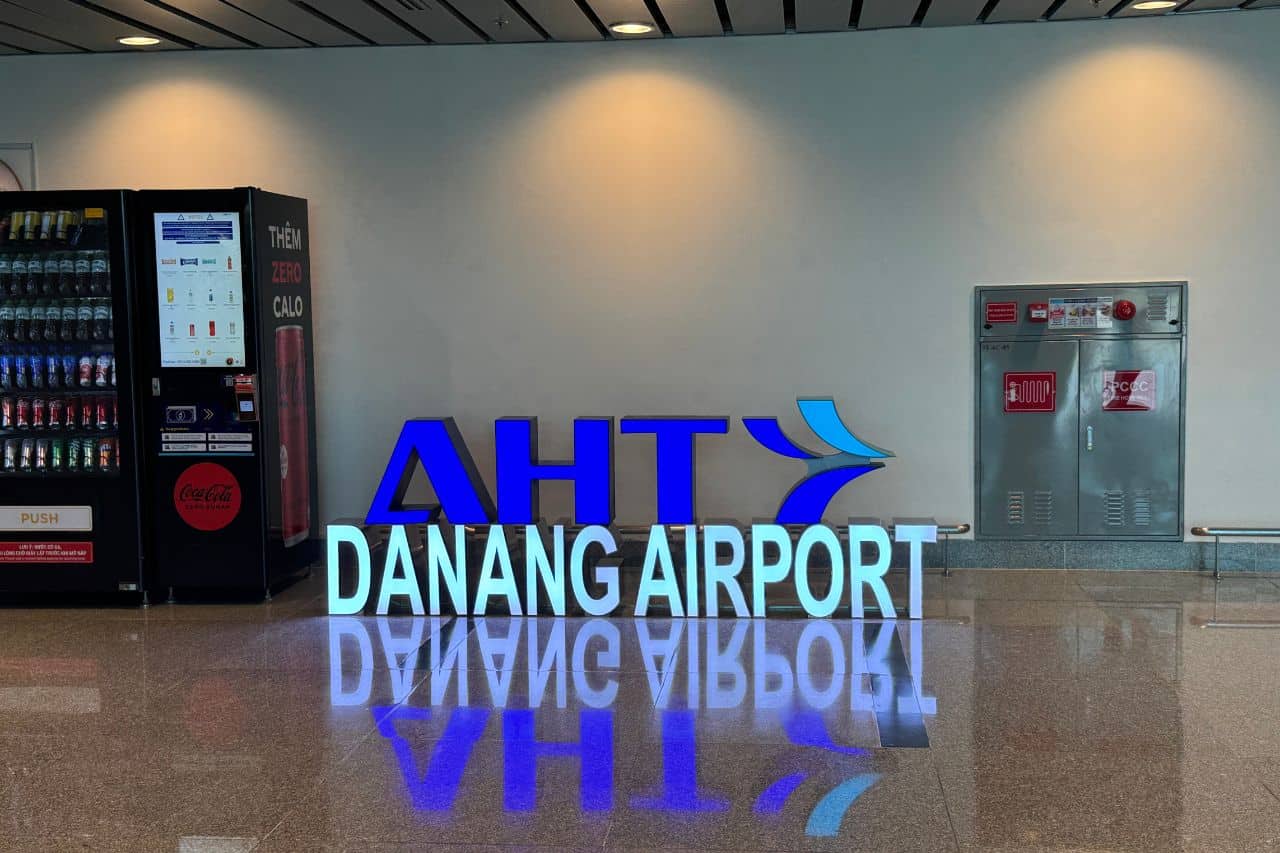 Illuminated Da Nang Airport sign next to vending machines and fire safety equipment in a modern terminal setting