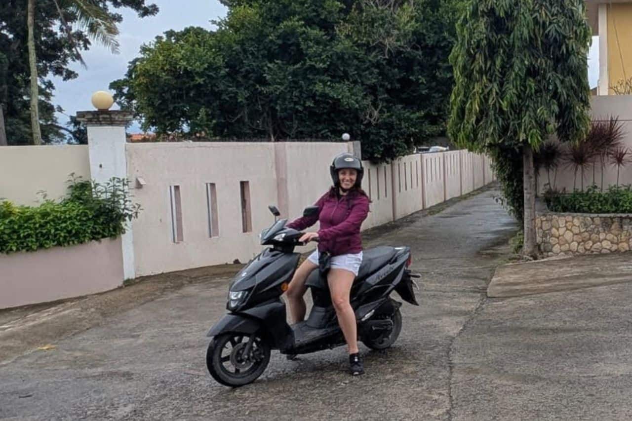 Woman on a black scooter in Asia wearing a purple rain coat
