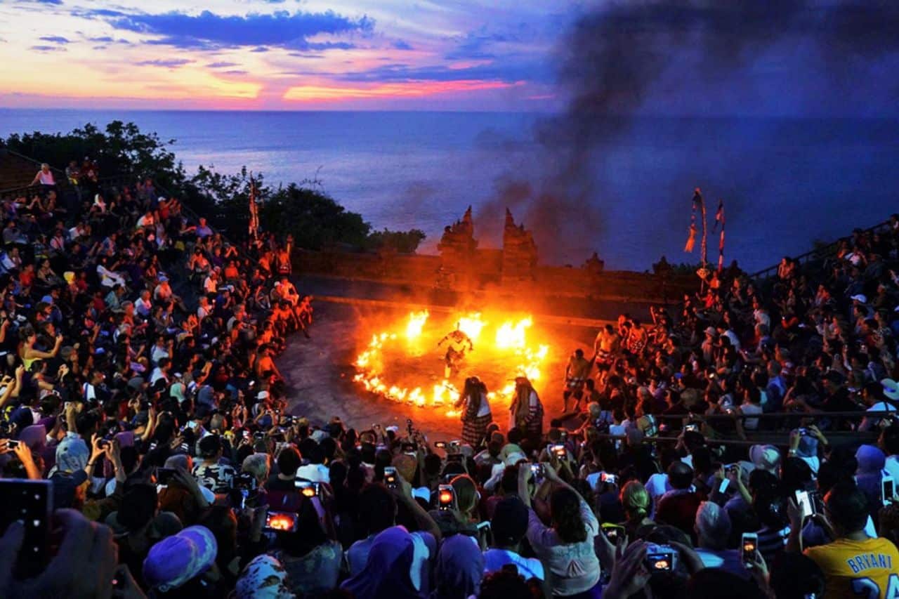 Spectators watching the famous Kecak Fire Dance at Uluwatu Temple with ocean views at sunset.