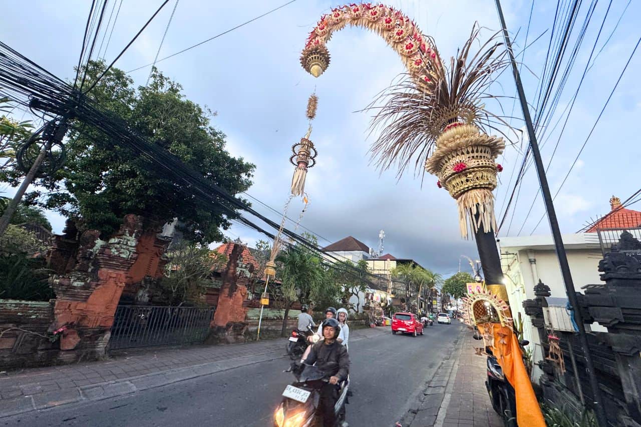 Street in Canggu Bali decorated with tall Penjor bamboo poles during a local ceremony.