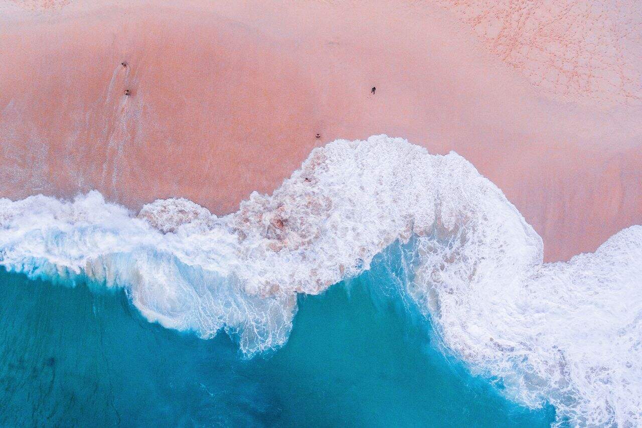 Overhead shot of pink sand beach and clear turquoise waves at Komodo Island.