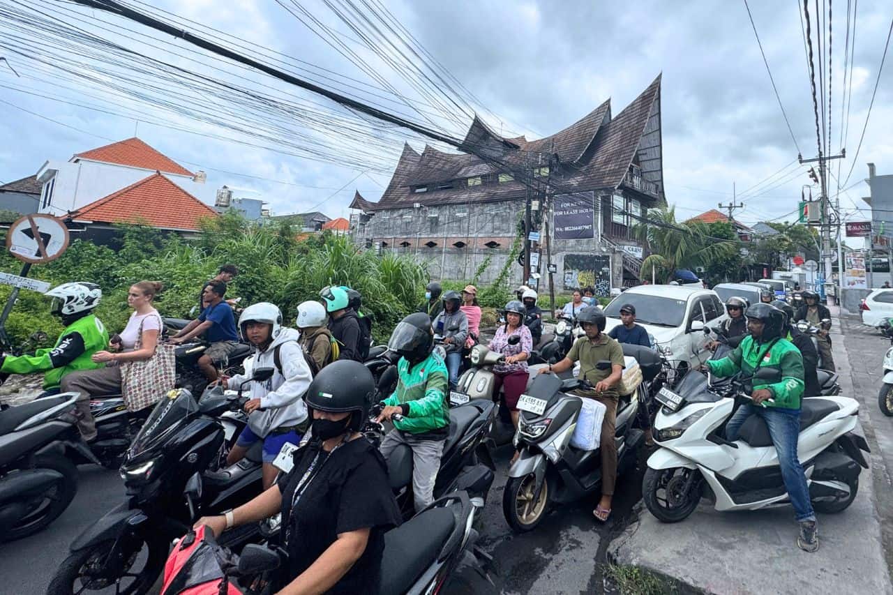 Crowded street in Canggu with dozens of scooters and riders navigating through traffic.