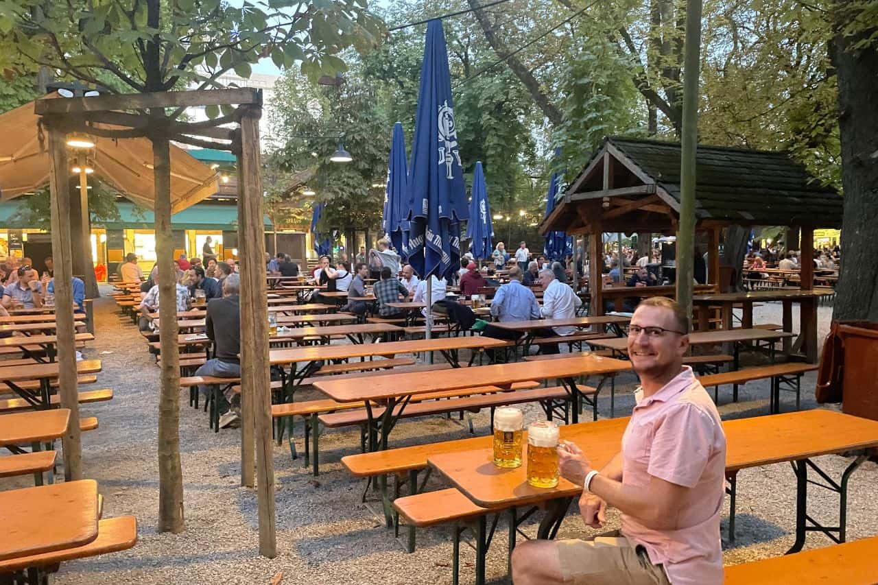 Man sitting at a traditional beer garden in Munich with wooden benches