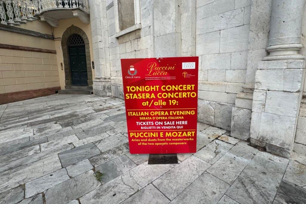 Red sign in Lucca Italy advertising a live Puccini concert held nightly in the historic center