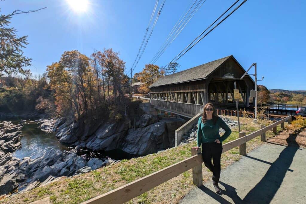 Traveler standing near the historic covered bridge in Ludlow Vermont during fall foliage season